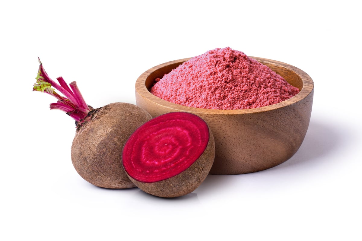 Beetroot powder in wooden bowl with fresh fruit isolated on white background