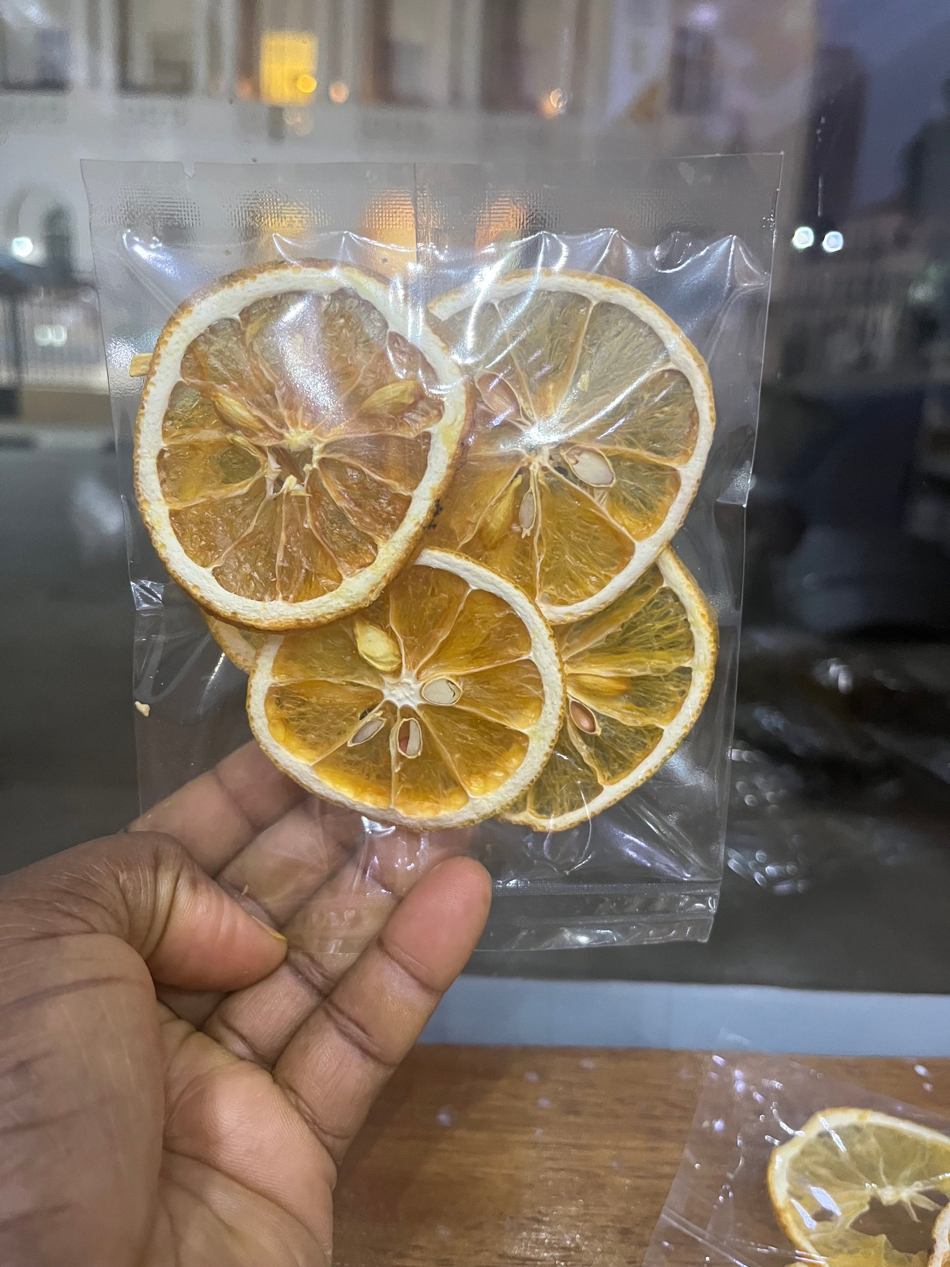 Mão segurando pacote de laranjas desidratadas
