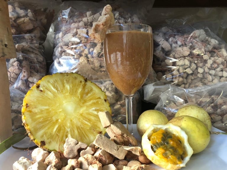 Pineapple half and passion fruits with nuts and glass of juice displayed on white surface