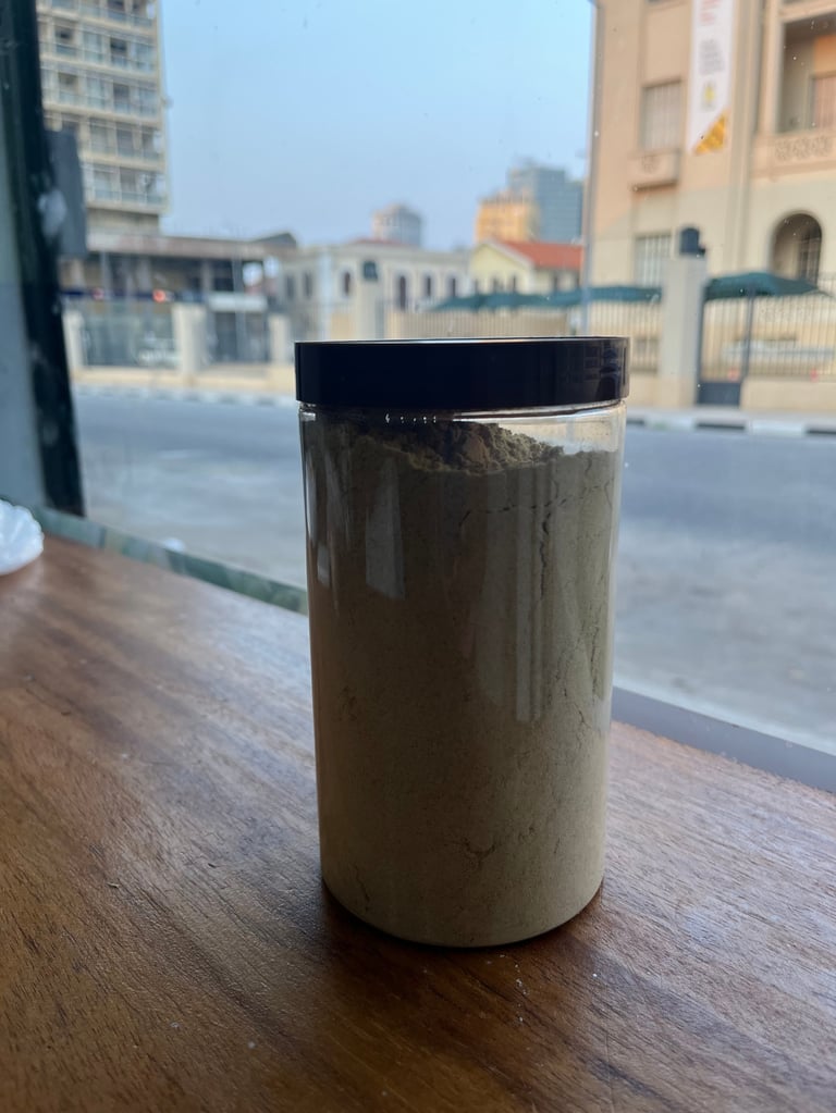 Coffee cup with black lid on wooden table with urban cityscape visible through window behind it